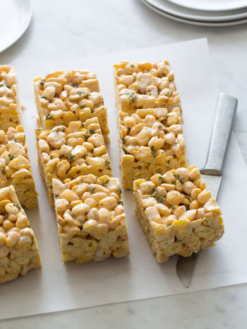 Simple browned butter, thyme, and Corn Pops cereal treat squares with a knife.