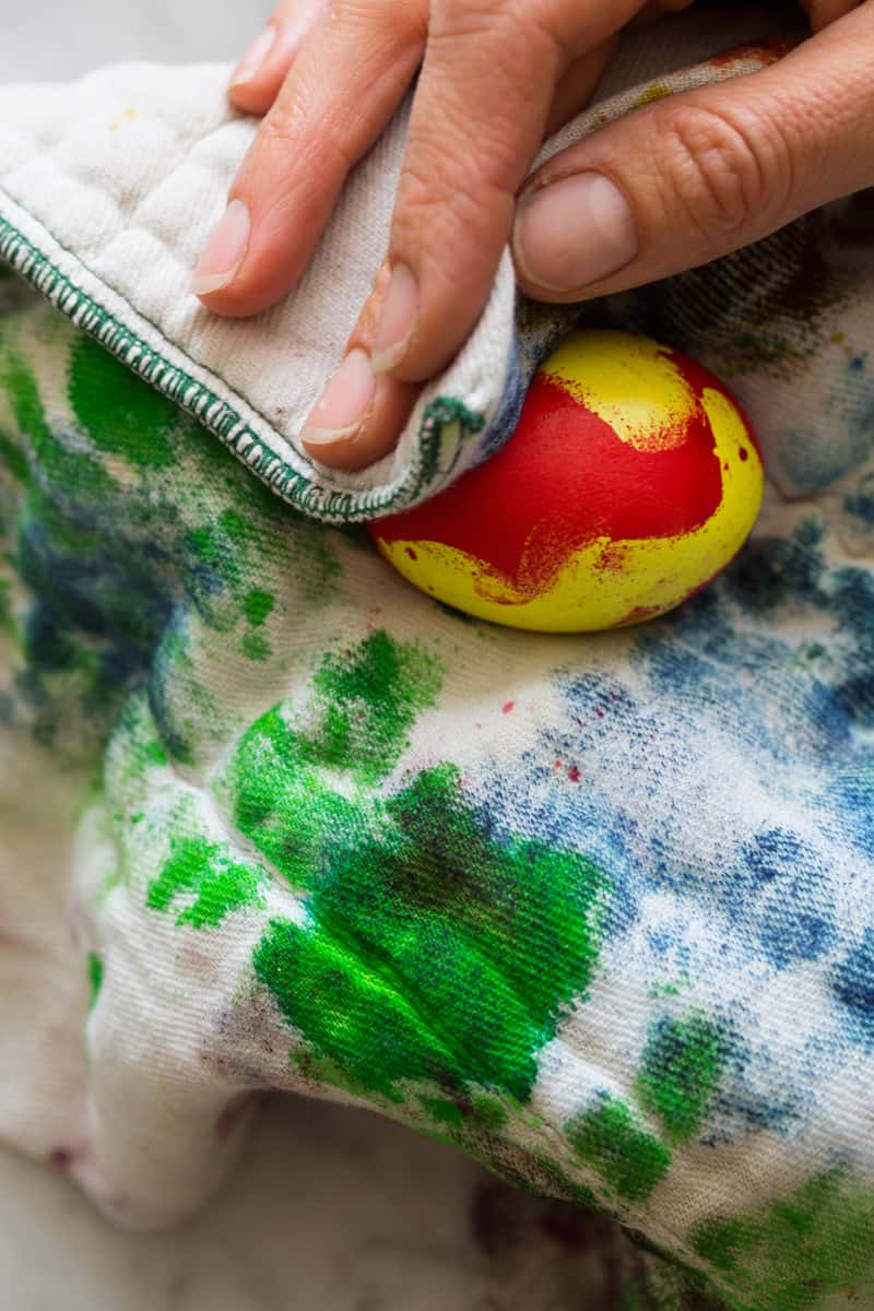 A red and yellow egg being wiped off with a rag.