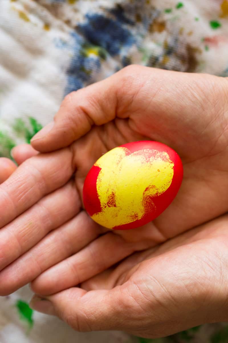 A finished red and yellow egg in a hand.