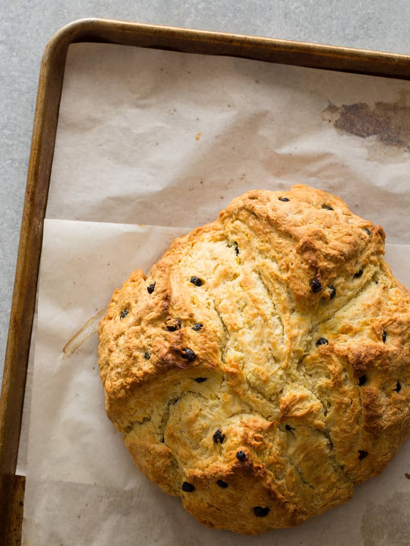 A top view of a loaf of Irish soda bread with dried blueberries on parchment paper.