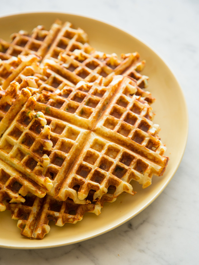 A close up of whole gruyere and green onion waffles on a plate.