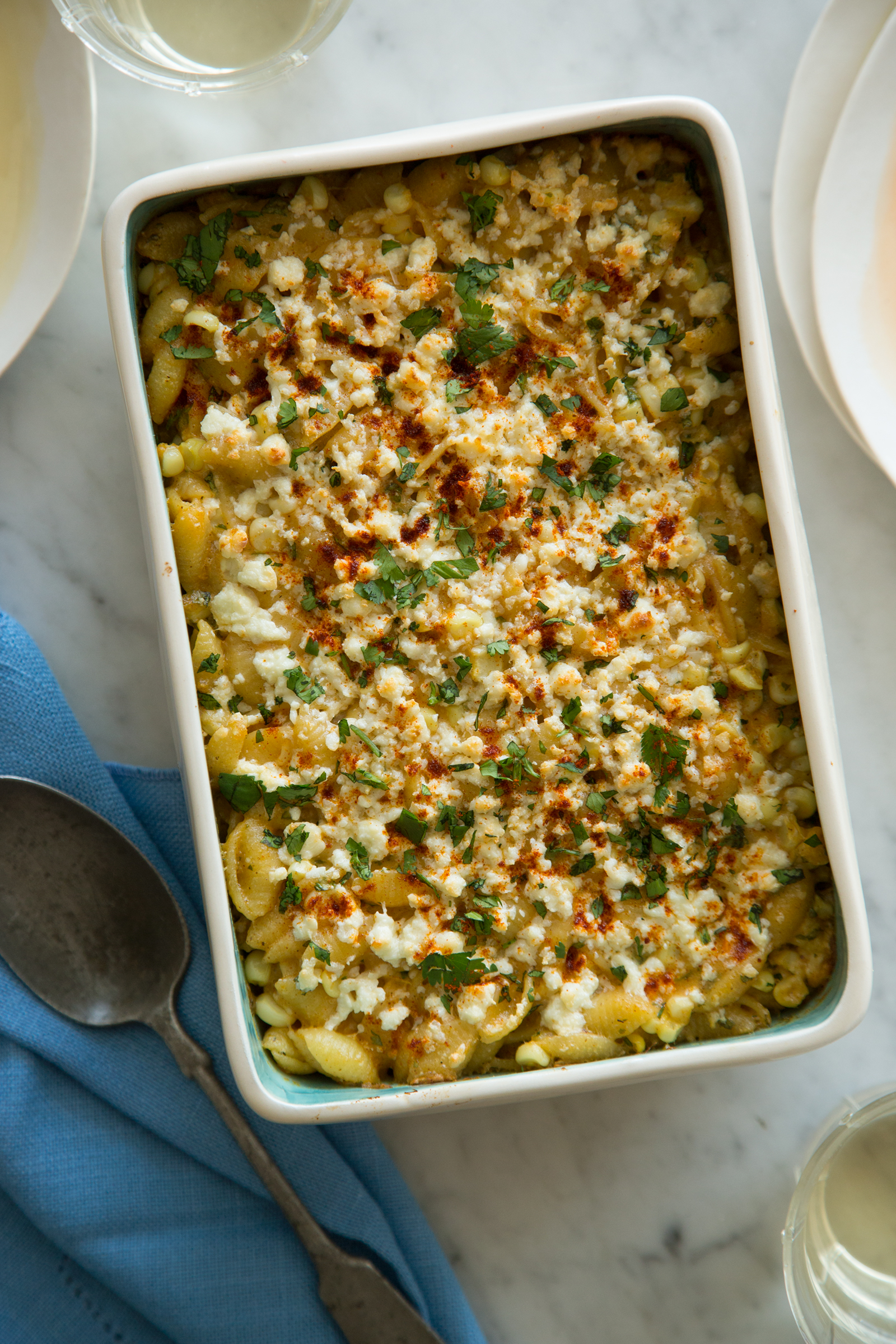 Elote mac and cheese in a baking dish with a spoon next to it.