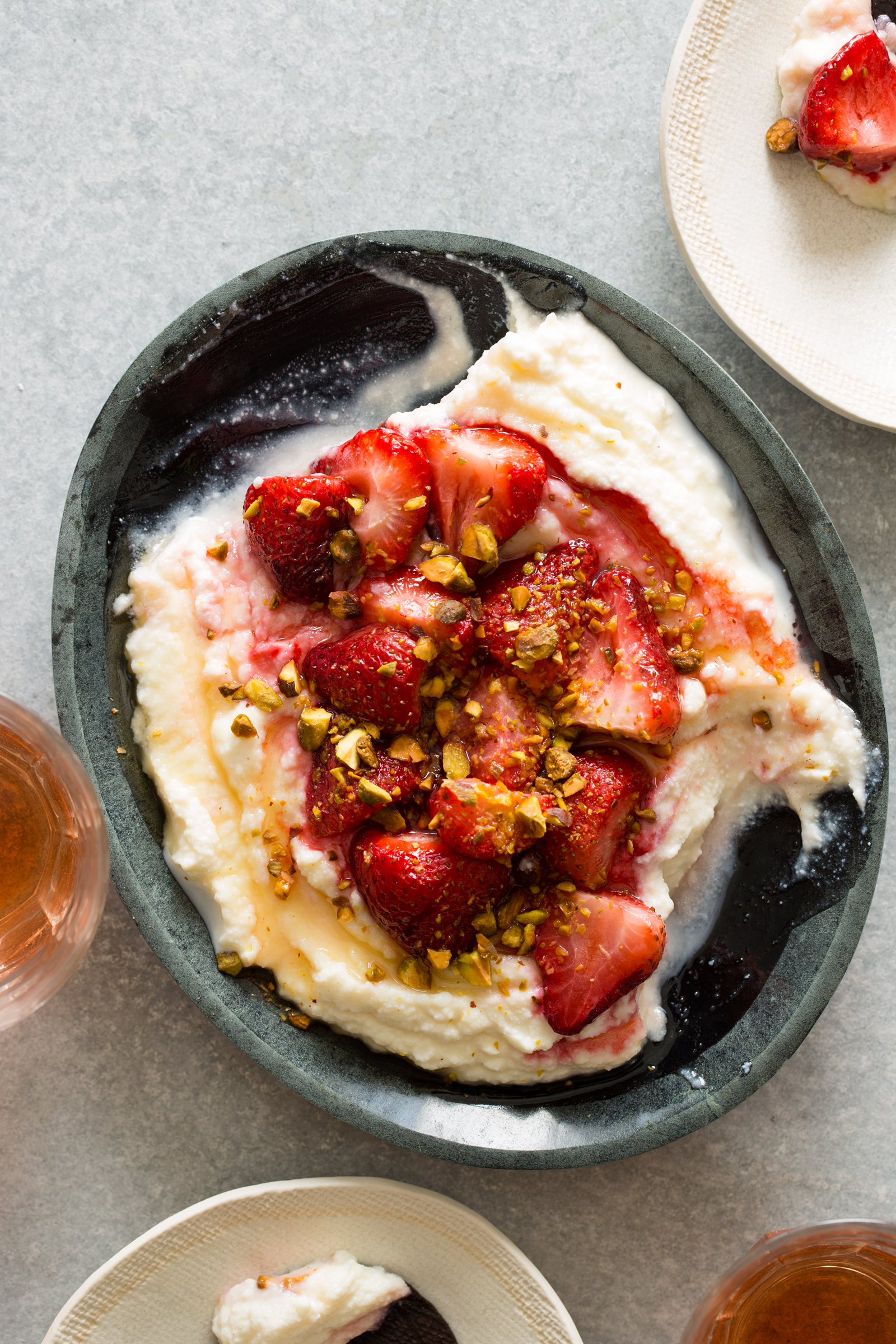 Whipped ricotta with roasted strawberries on top and some plates next to it.
