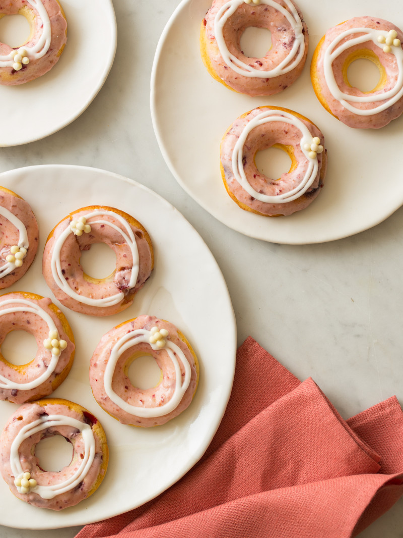 Plates of baked cherry doughnuts with cherry and vanilla glaze and white chocolate crispy balls.