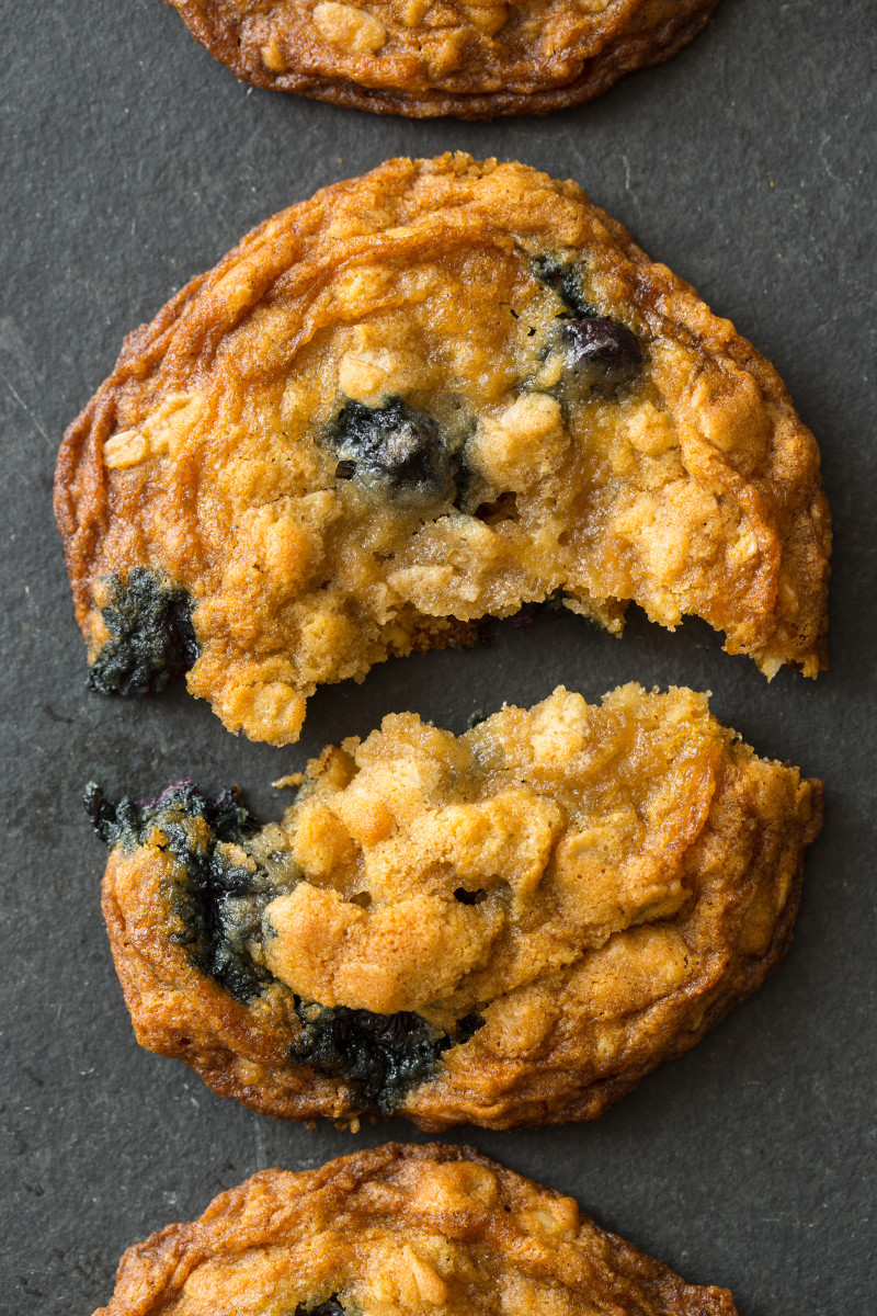 A close up of a blueberry and cardamom oat cookie broken in half.