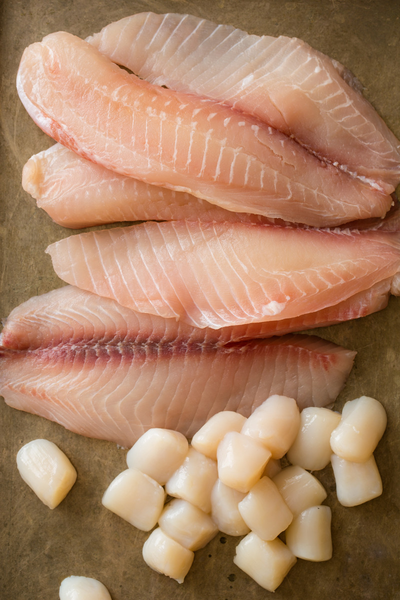 Raw tilapia fillets and bay scallops.