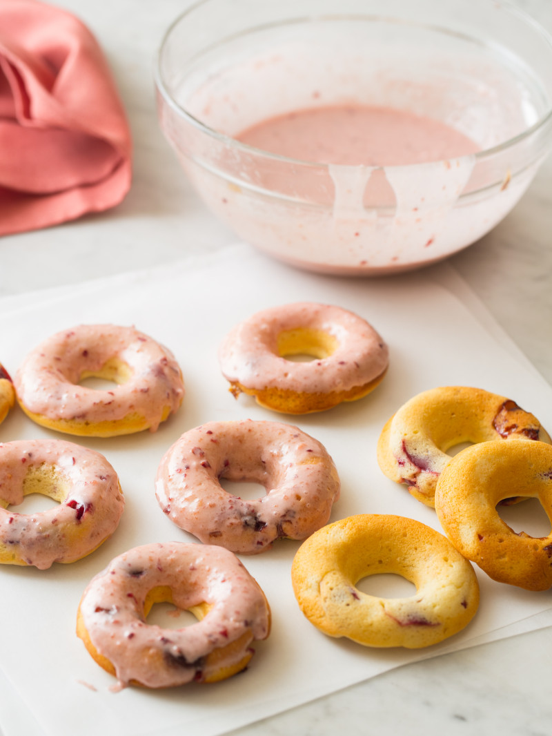 Baked cherry doughnuts with a bowl of cherry glaze.