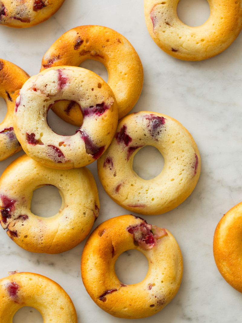 A close up of baked cherry doughnuts on a marble surface.