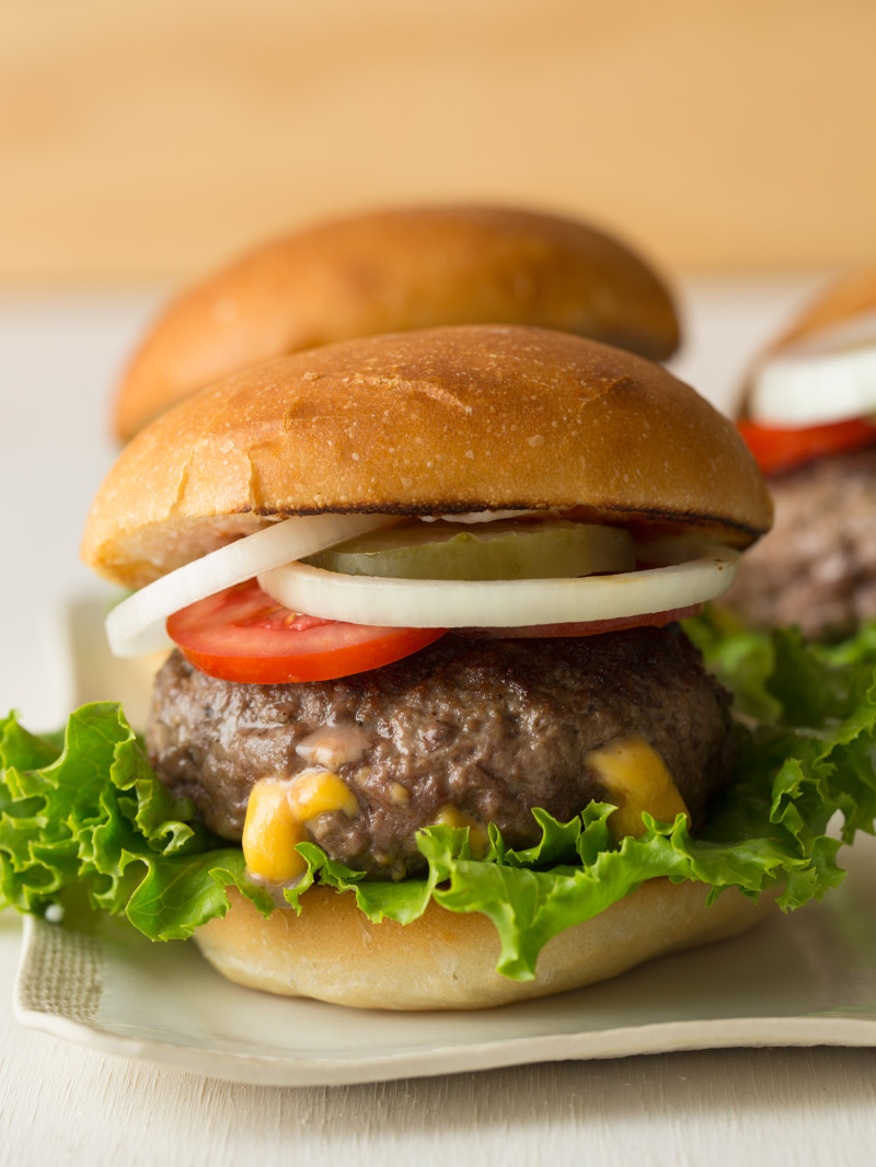 A close up of a juicy lucy burger with all the fixings.