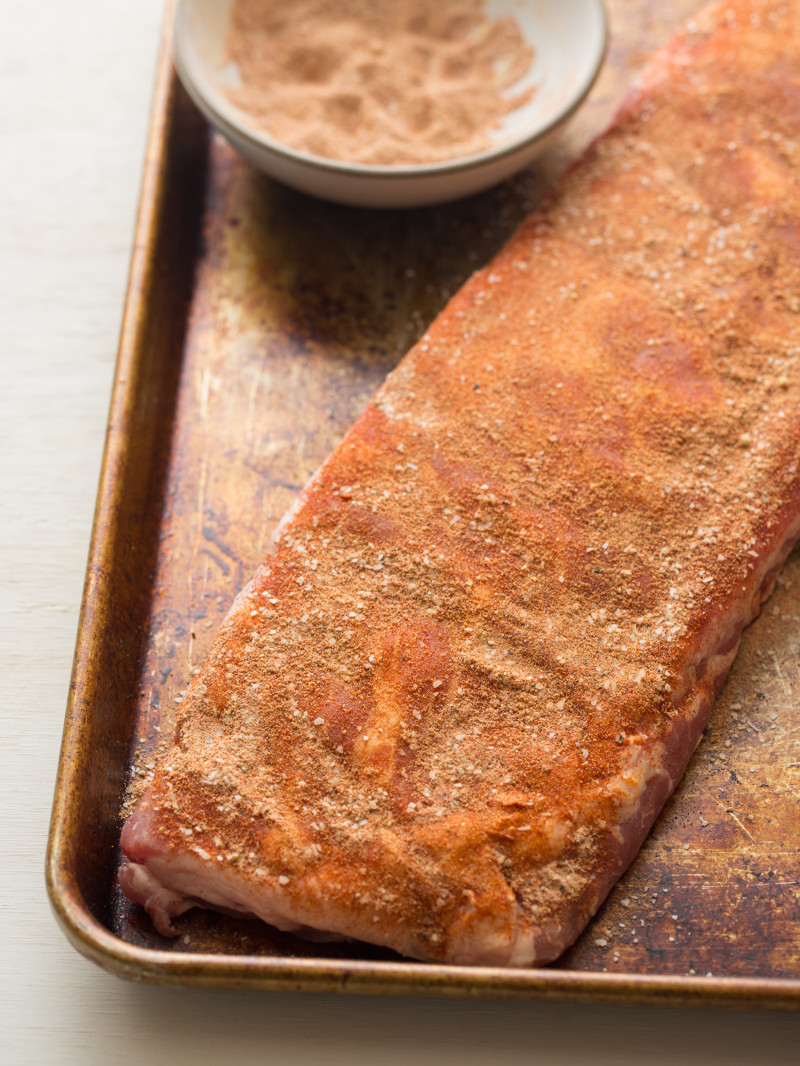 Spare ribs on a baking sheet rubbed with spices.