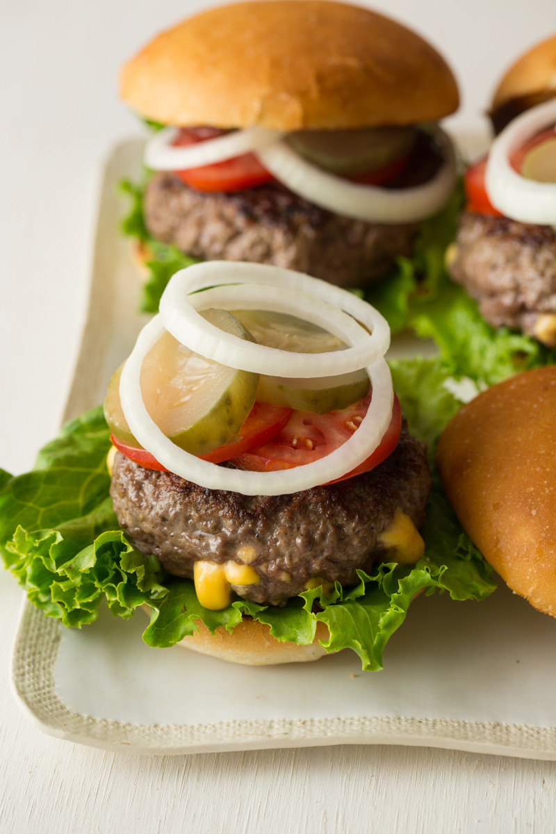 A close up of an open juicy lucy burger with all the fixings.