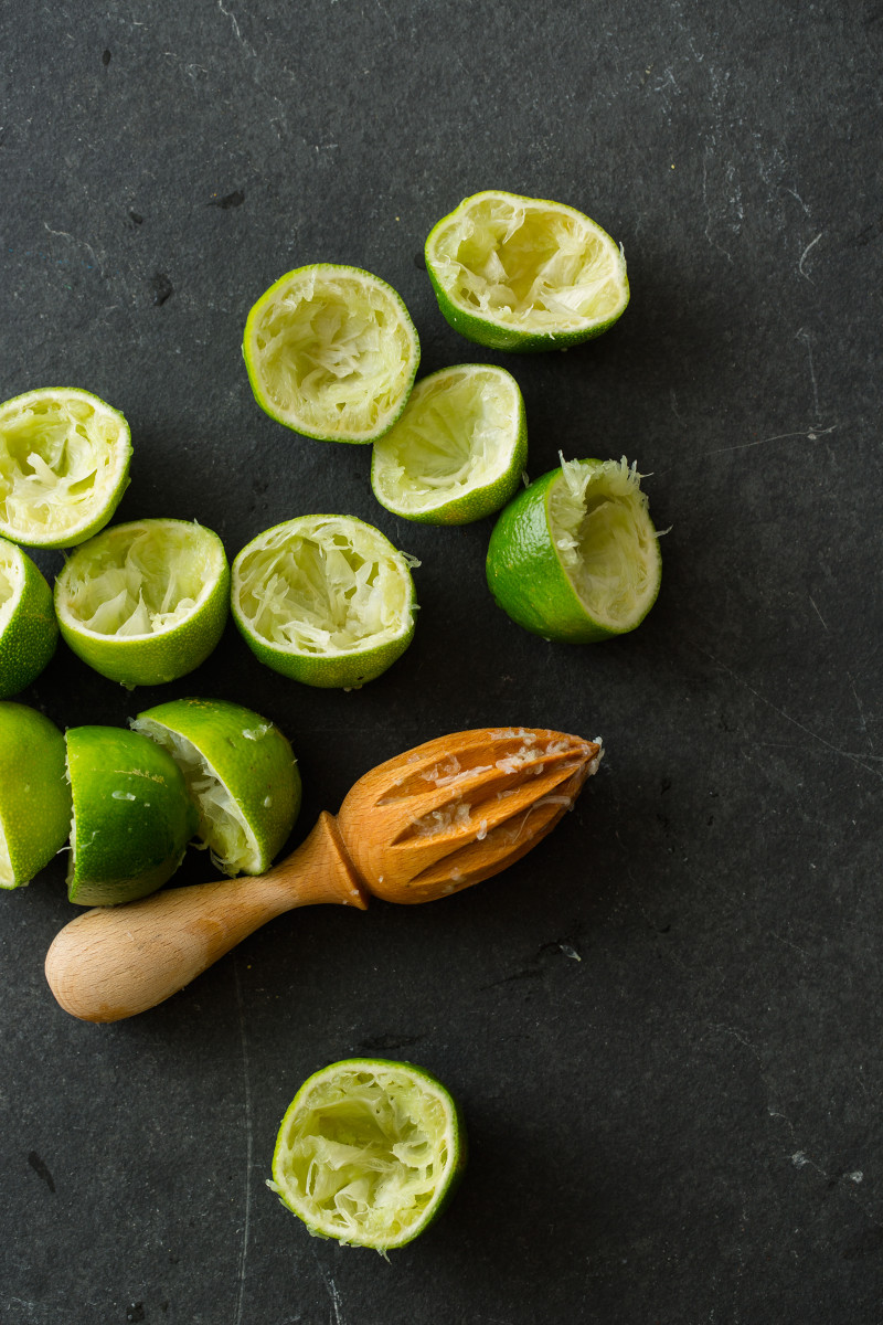 Juiced halved limes with a wooden citrus juicer.