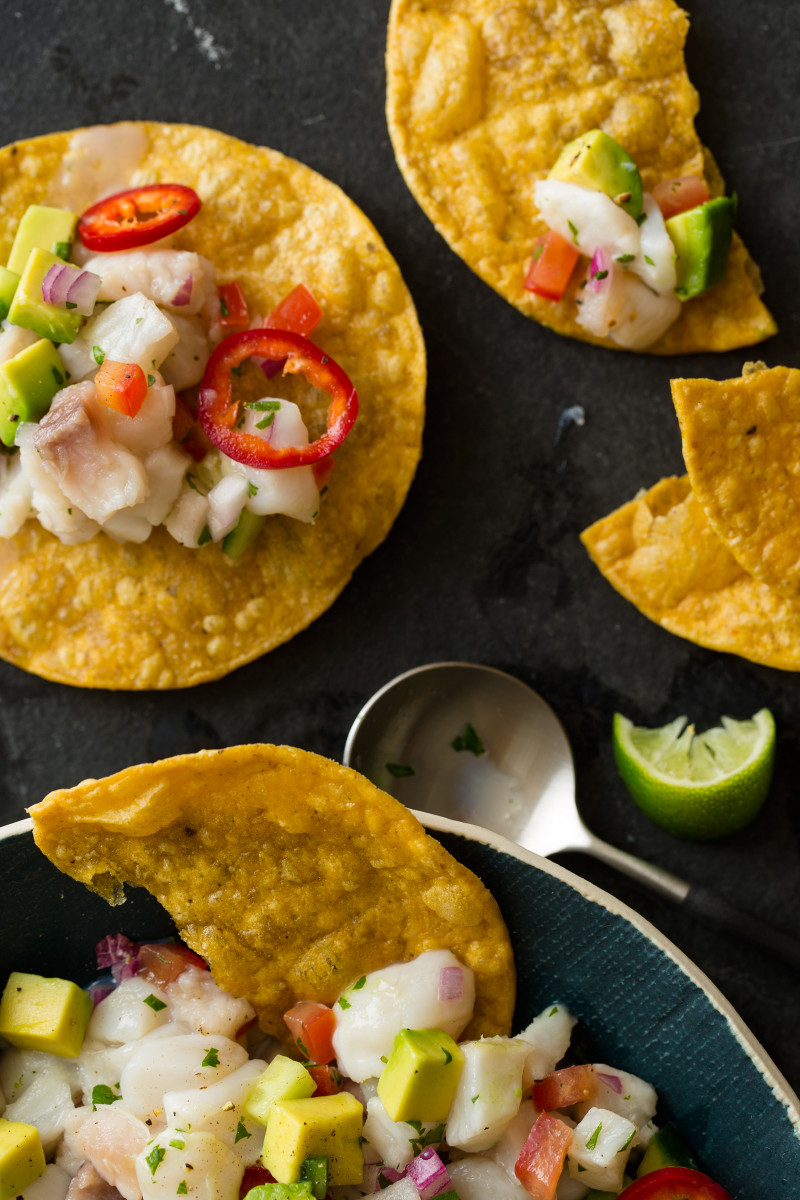 A close up of simple ceviche spooned onto tostadas with lime wedges.