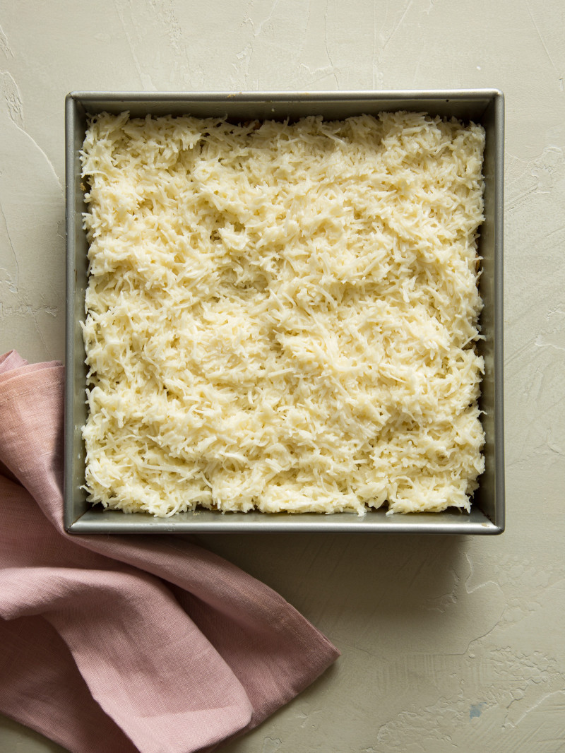 Unbaked coconut oat bars in a pan with a pink napkin.