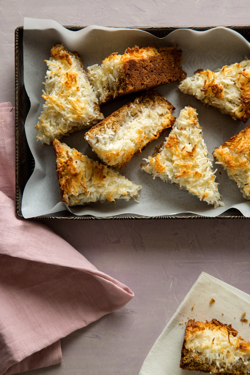 Several triangle cut pieces of coconut oat bars in a pan with pink napkins.