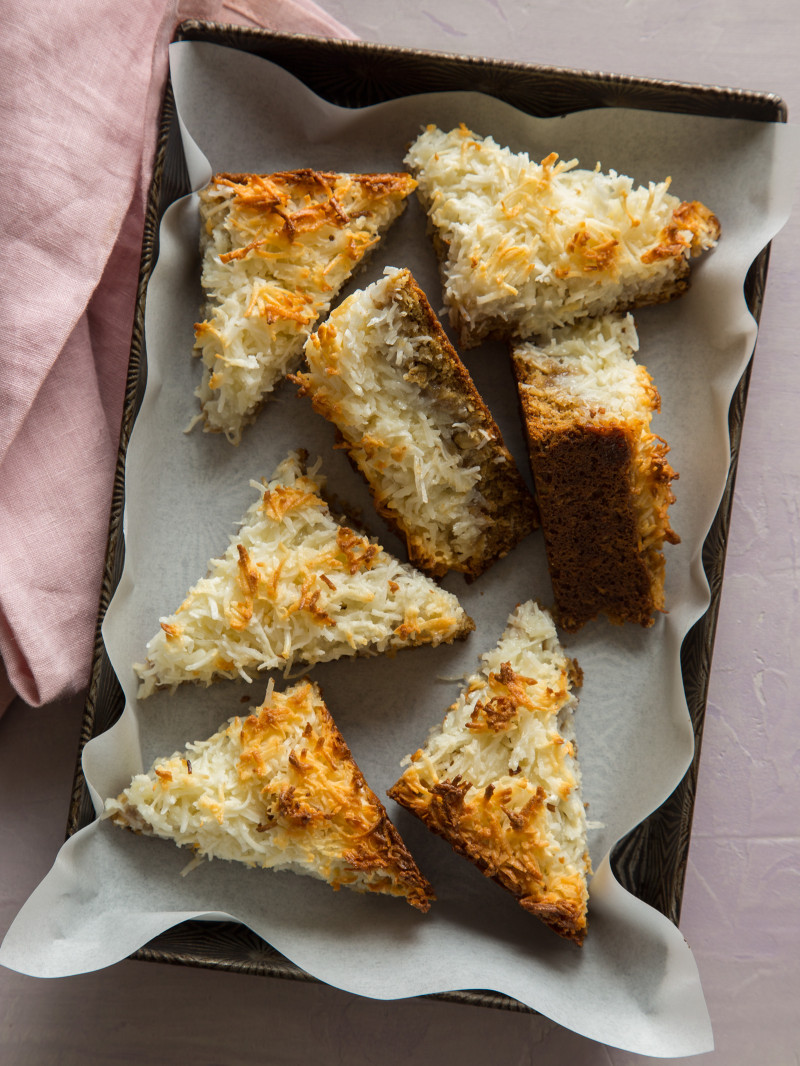 Several triangle cut pieces of coconut oat bars in a pan.