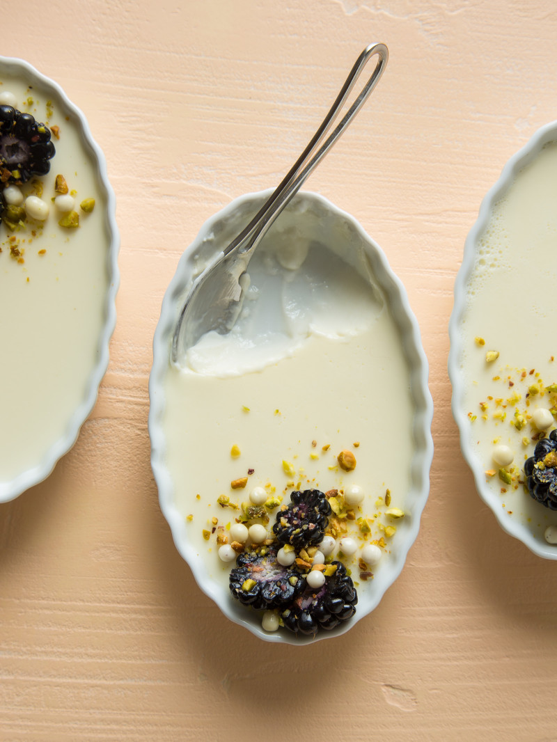 A close up of creme fraiche panna cotta with a spoon and bites taken out.