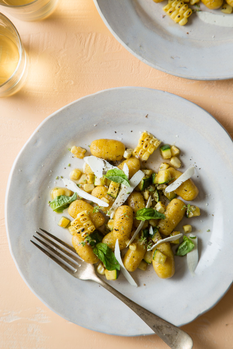 Summer gnocchi with charred sweet corn and zucchini on a plate with a fork.