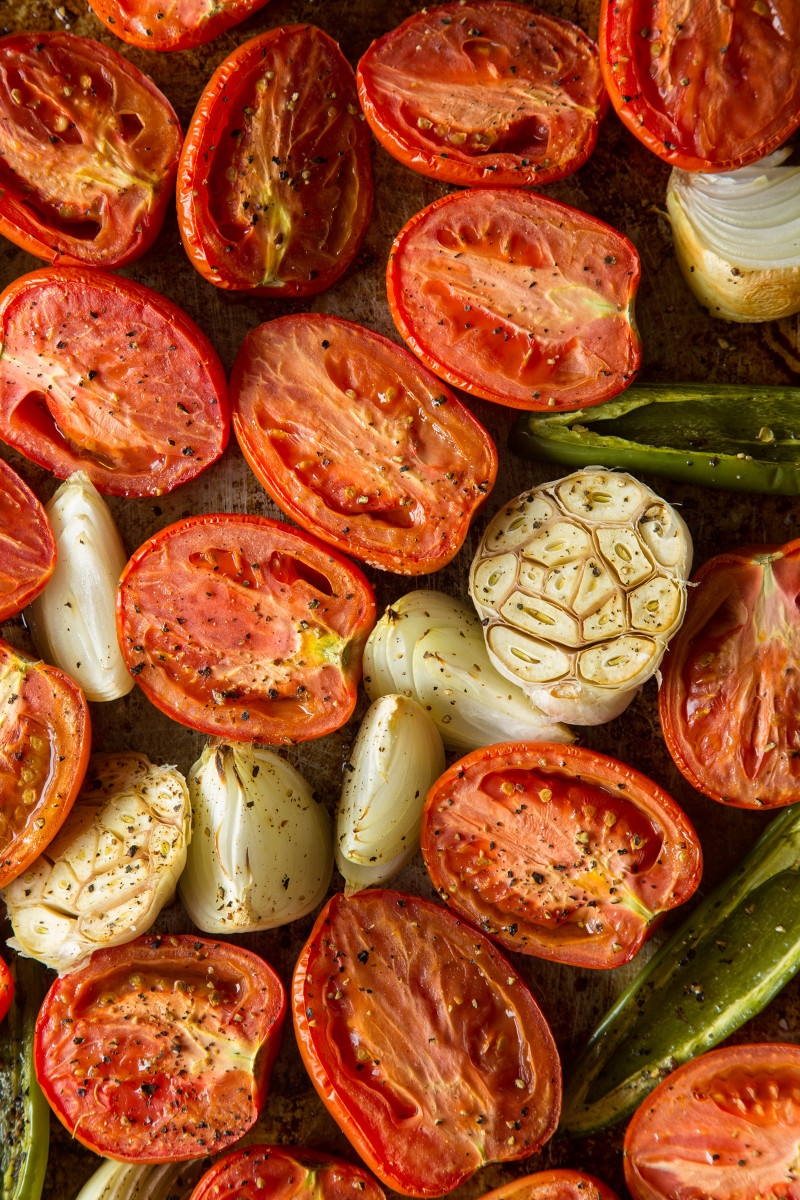 Freshly roasted tomato salsa ingredients on a baking sheet. 