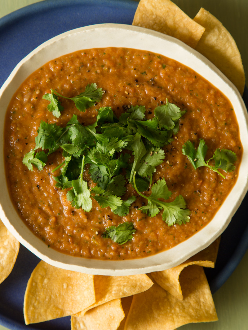 Tomato Salsa in a bowl with cilantro on top and tortillas chips on the side. 