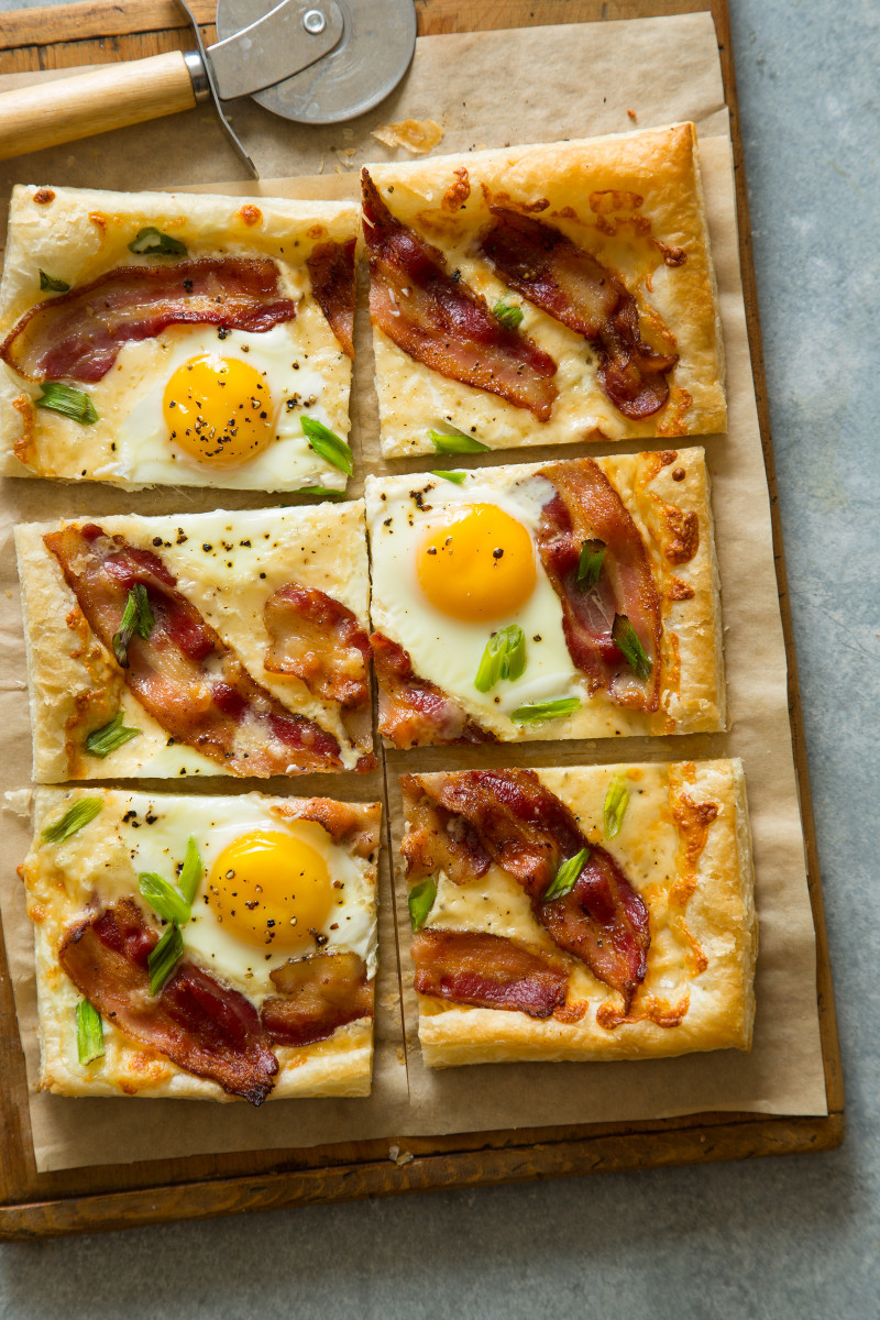 A sliced breakfast tart on parchment paper and a wooden cutting board.