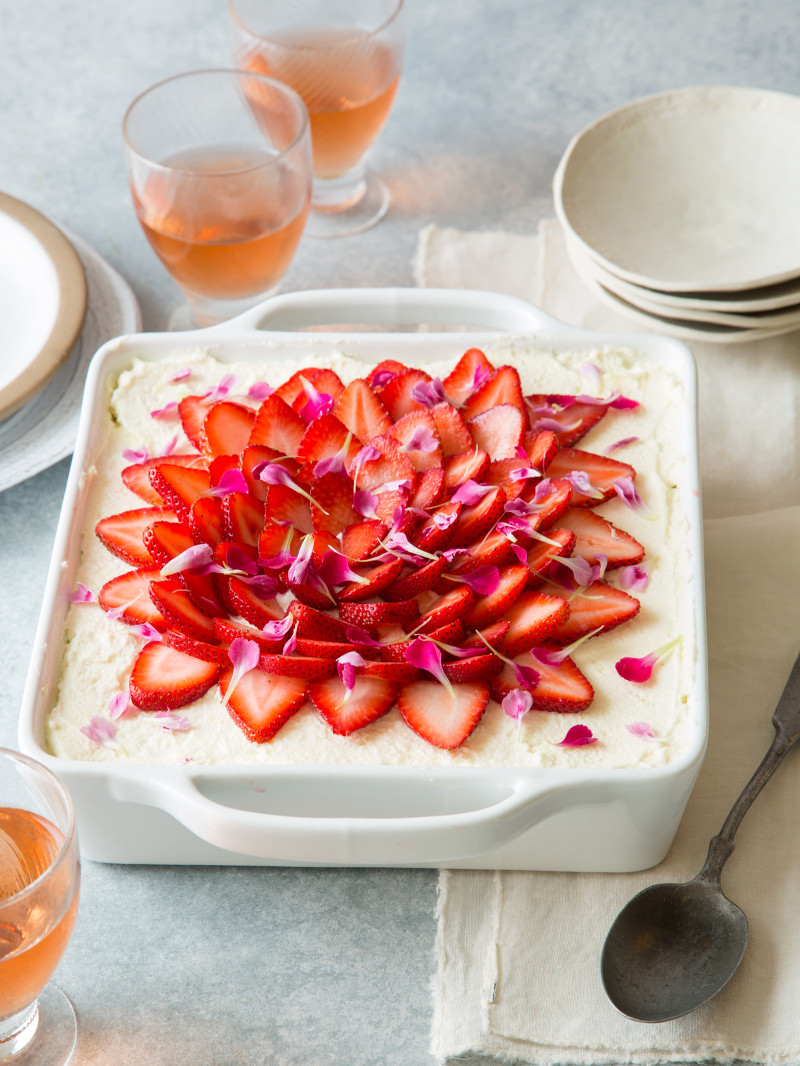 A strawberry tiramisu with plates and drinks.