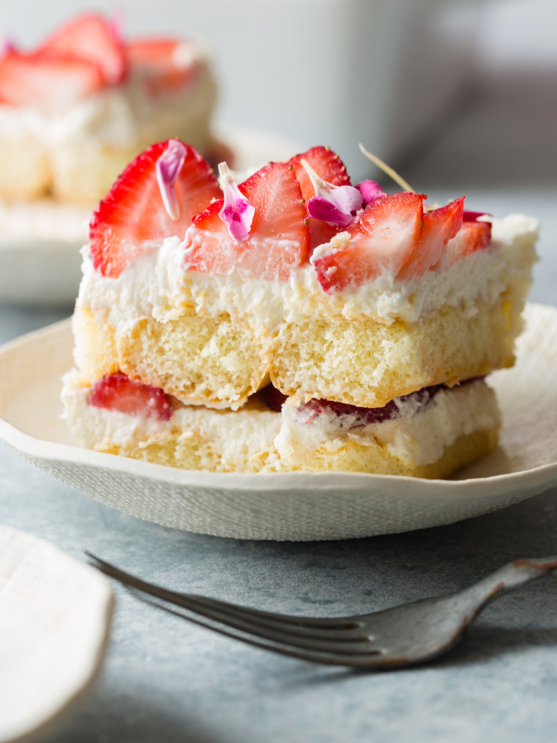 A close up of a piece of strawberry tiramisu with a fork.