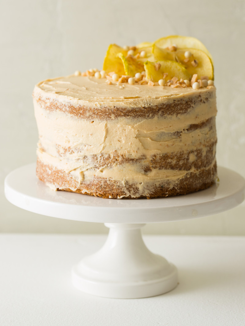 A whole apple thyme cake with salted caramel buttercream on a white cake stand.