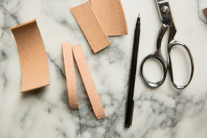 A close up of leather pieces, scissors, and a pen.