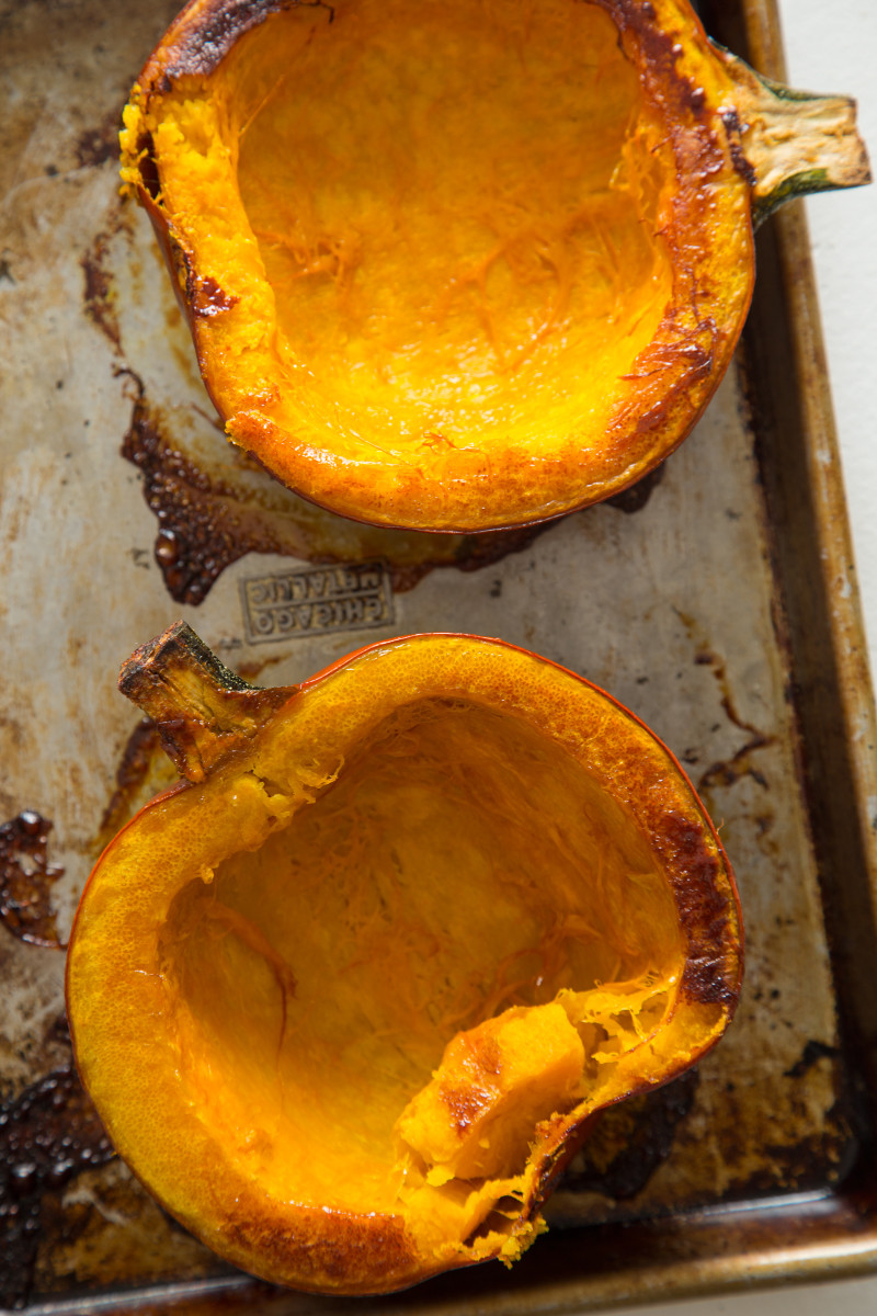 Roasted halved pumpkins on a sheet pan.