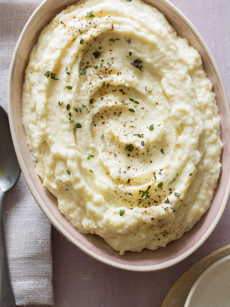 Cauliflower, parsnip, and roasted garlic mash in a bowl with a spoon.