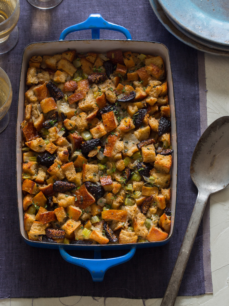 A pan of fig, herb, and sausage stuffing with a serving spoon.