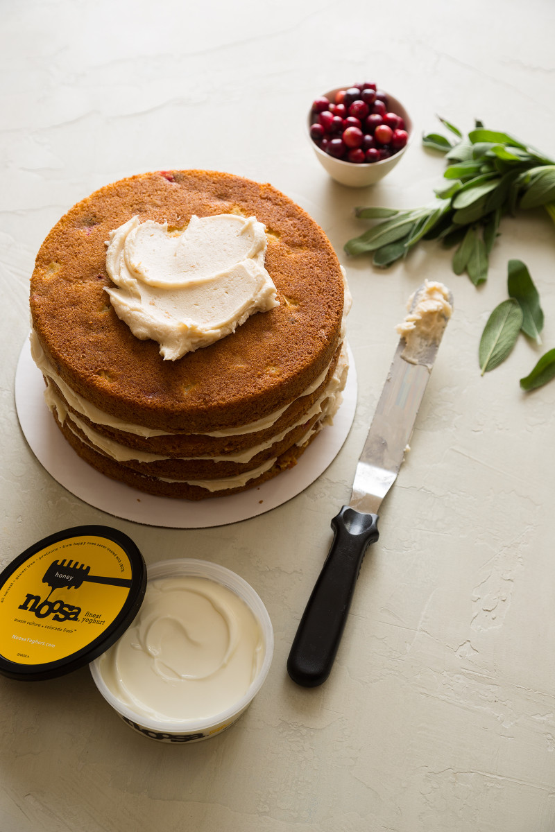 A naked apple cranberry cake layered with Noosa honey yoghurt with yoghurt and a spatula.