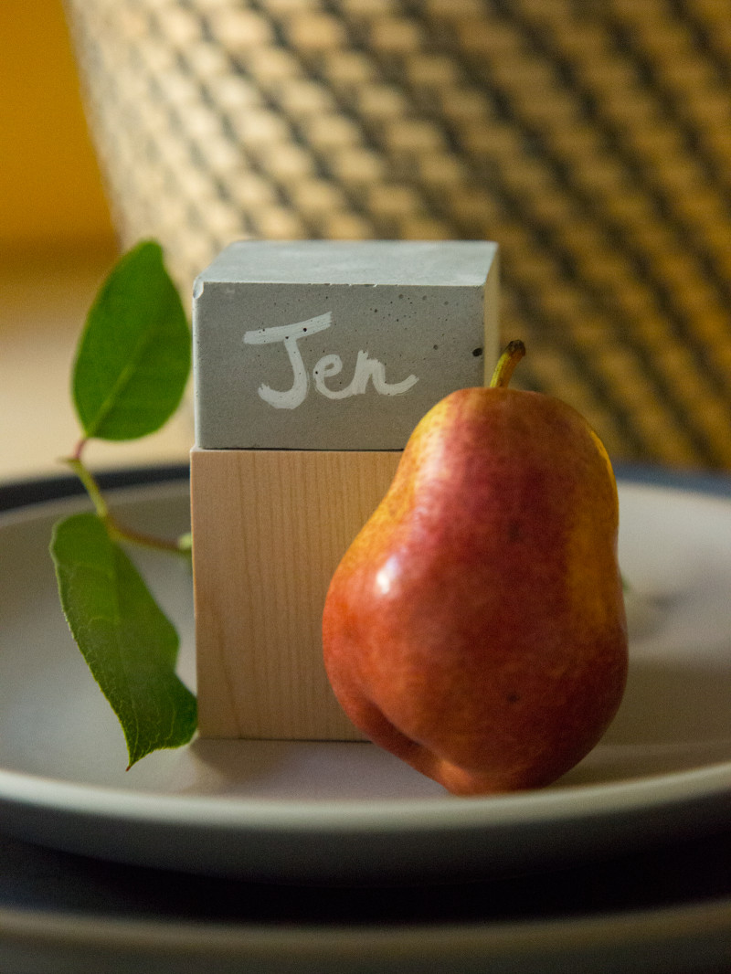 A close up of a DIY cement and wood place card with a pear.