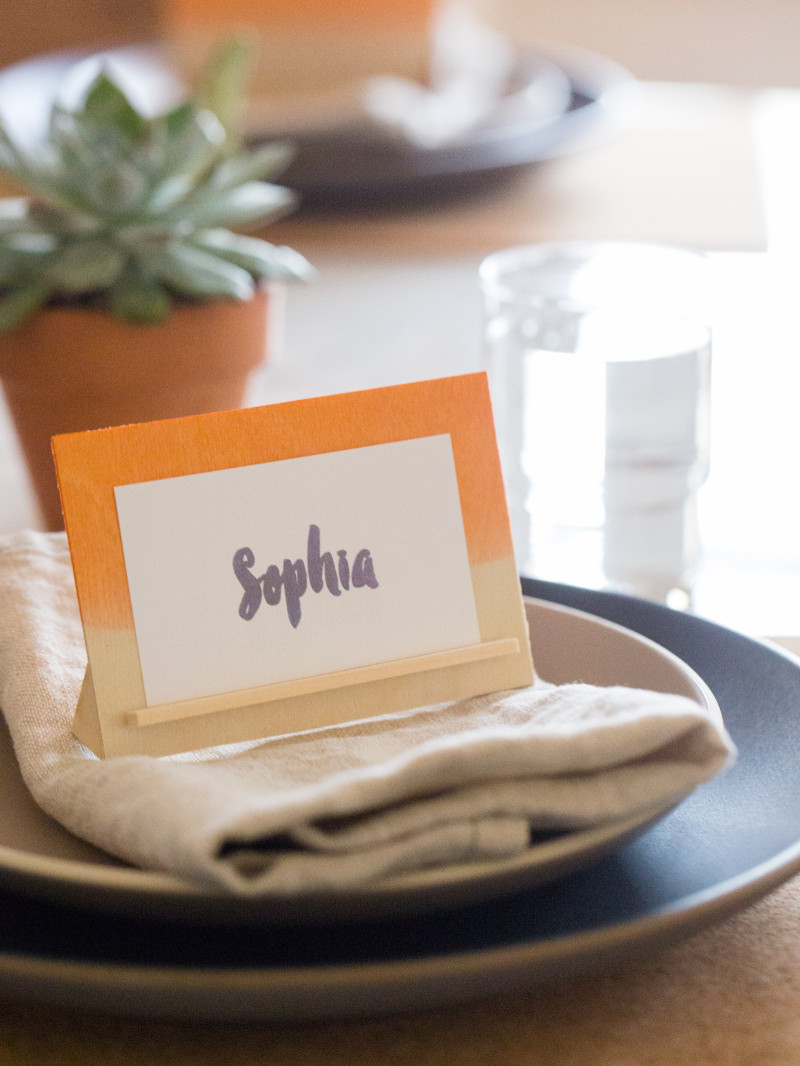 A DIY dip dye wood place card holder on a place setting.
