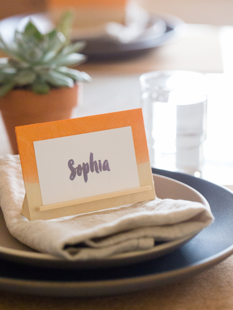 A DIY dip dye wood place card holder on a place setting.