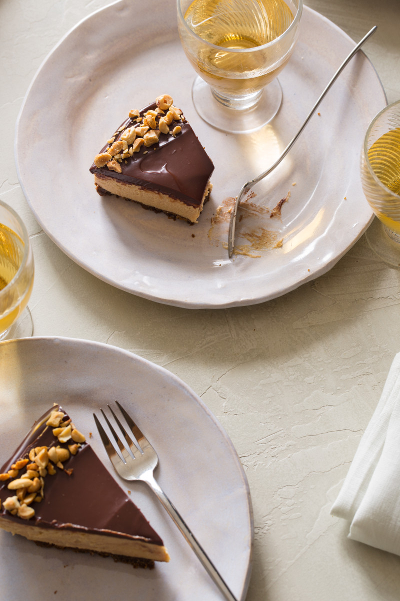 No bake peanut butter cheesecake with dark chocolate ganache slices on plates with forks.