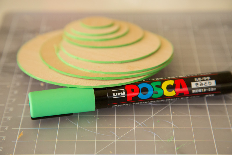 Wooden circles in different sizes with   green edges and a green paint pen.