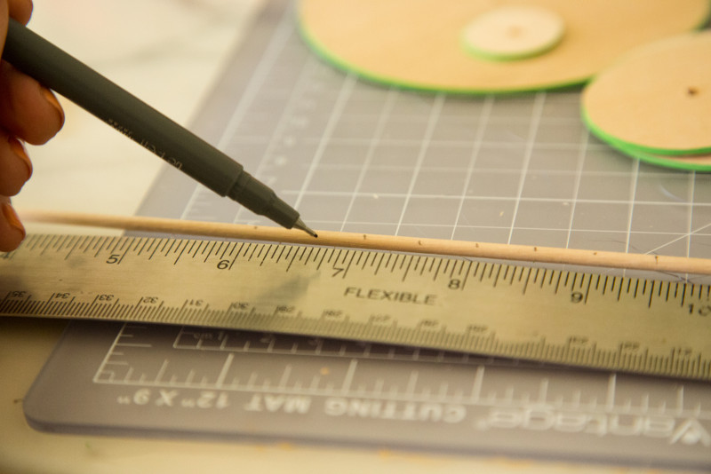 A close up of a dowel being measured and marked.