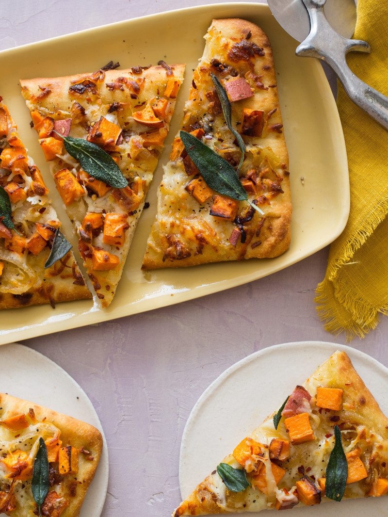 Slices of sweet potato and caramelized onion flatbread on a platter and served on plates.