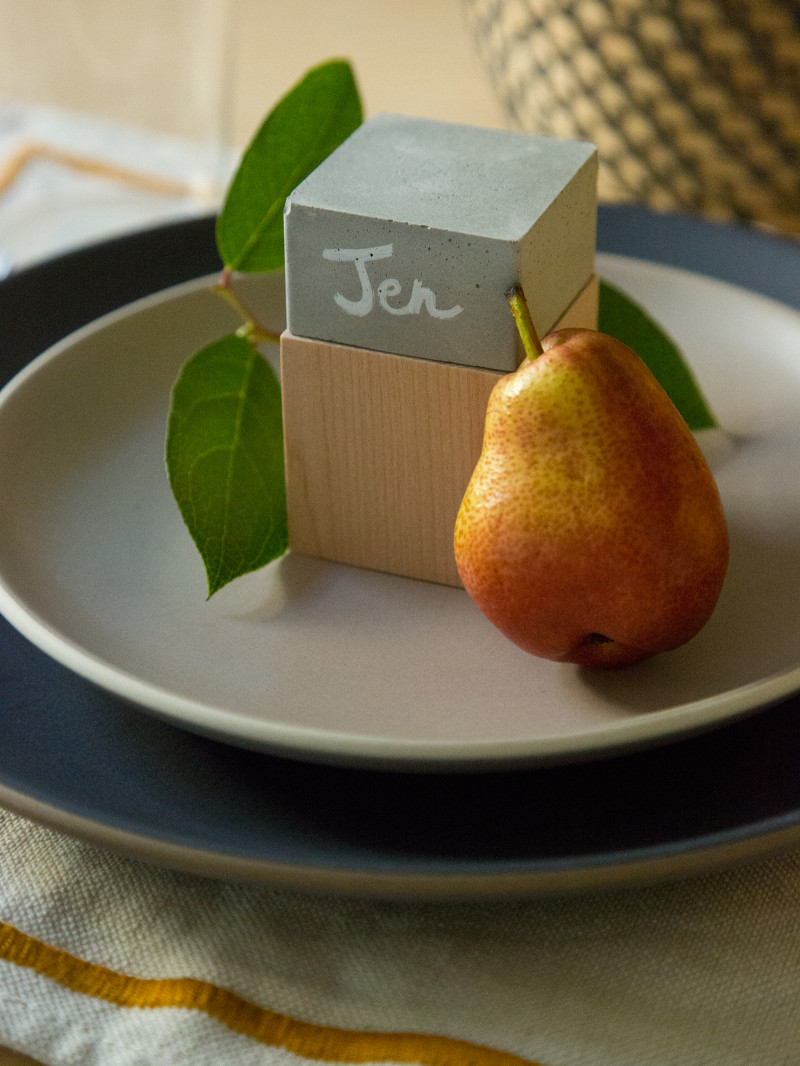 A DIY cement and wood place card with a pear on a place setting.