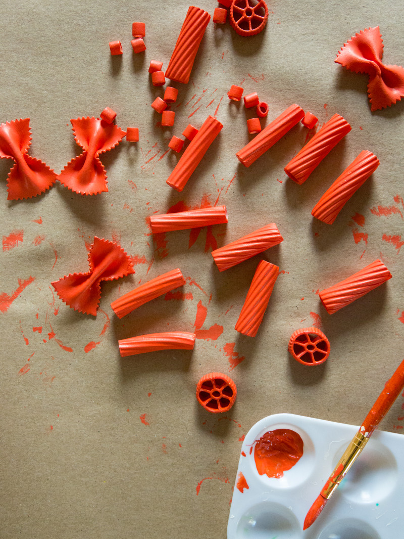 Different types of dry pasta noodles painted red to use for DIY pasta gift wrap.