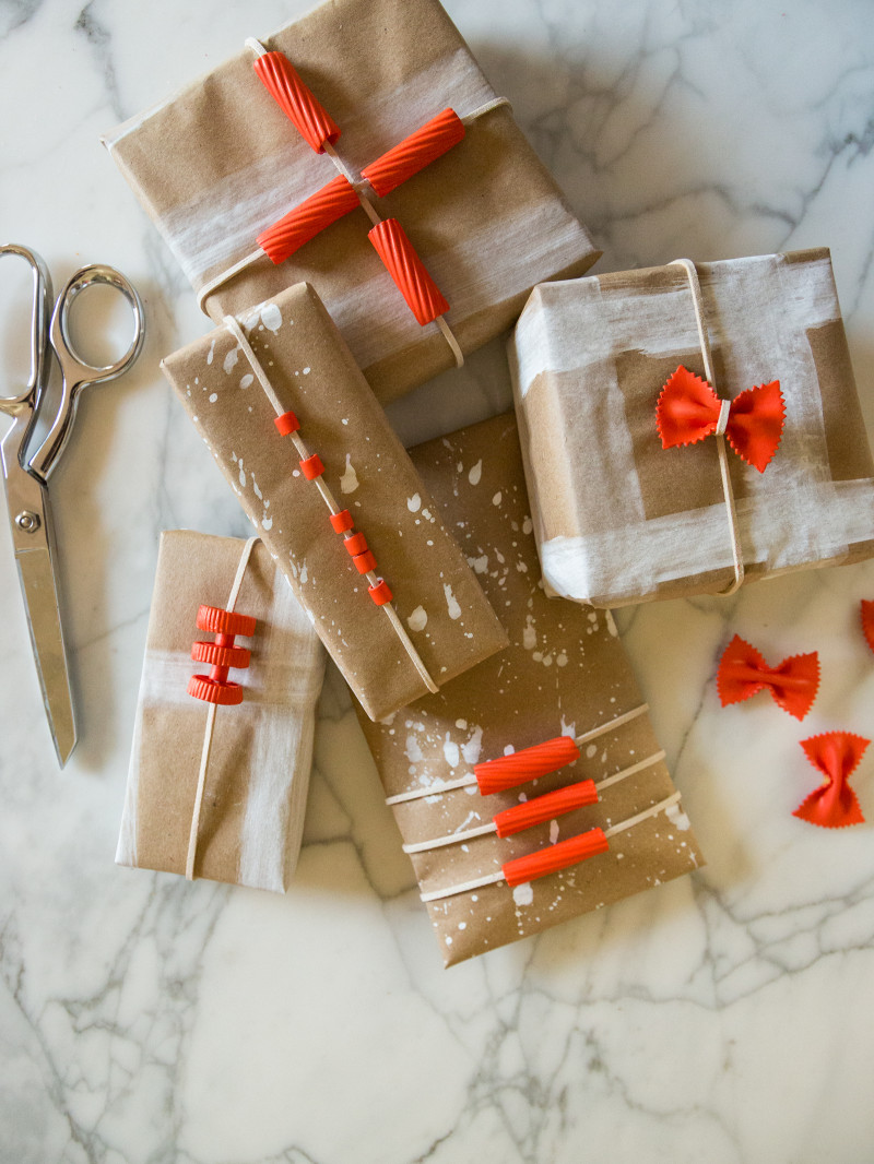 A variety of boxes wrapped in DIY pasta gift wrap with scissors.