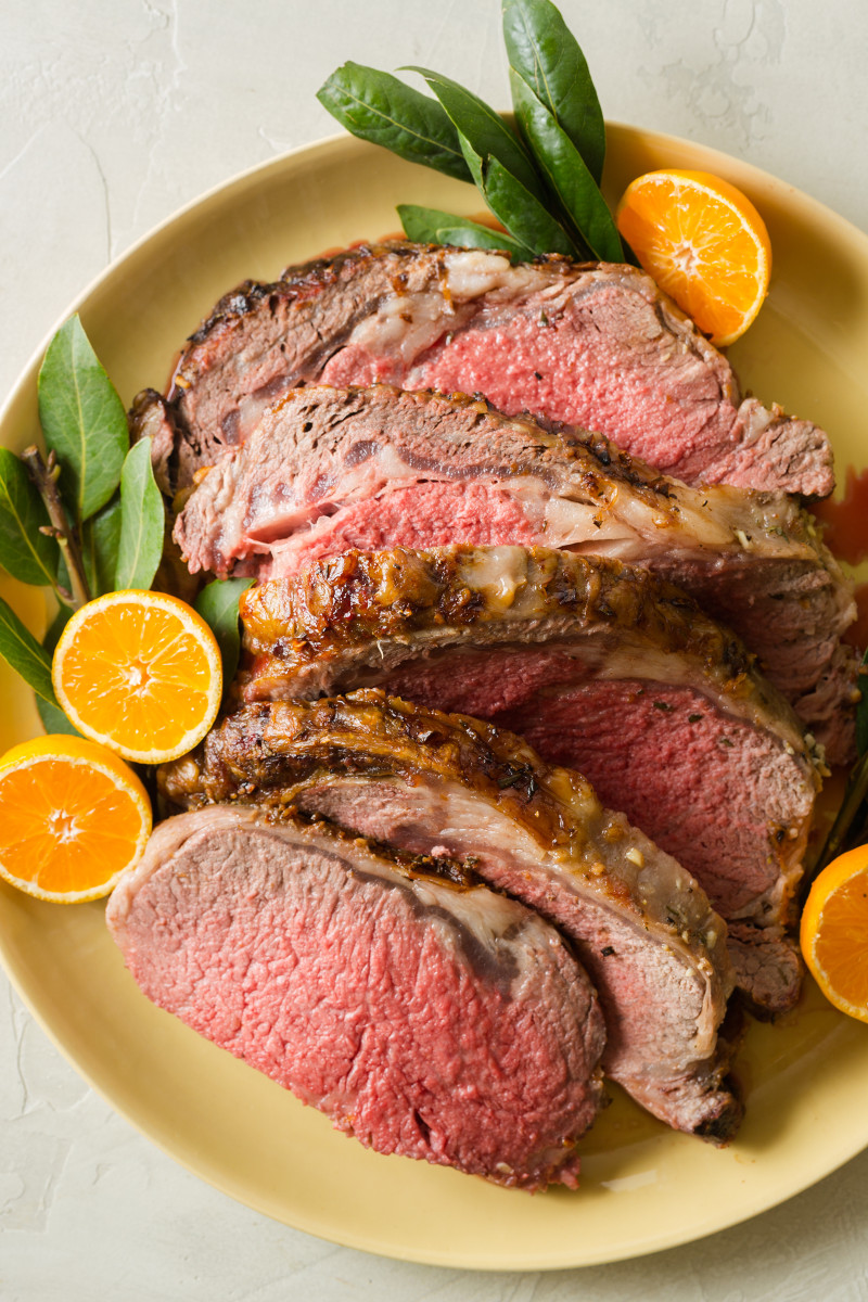 A plate of sliced standing rib roast garnished with orange halves.