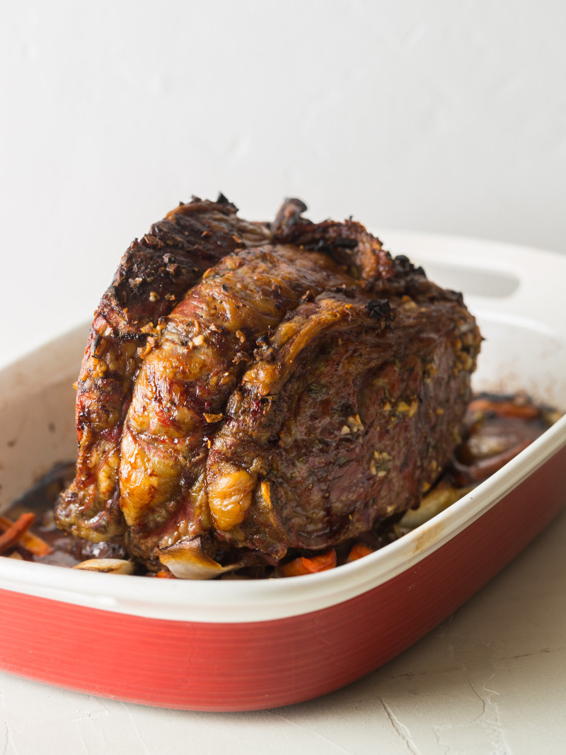 A cooked standing rib roast in a baking pan.