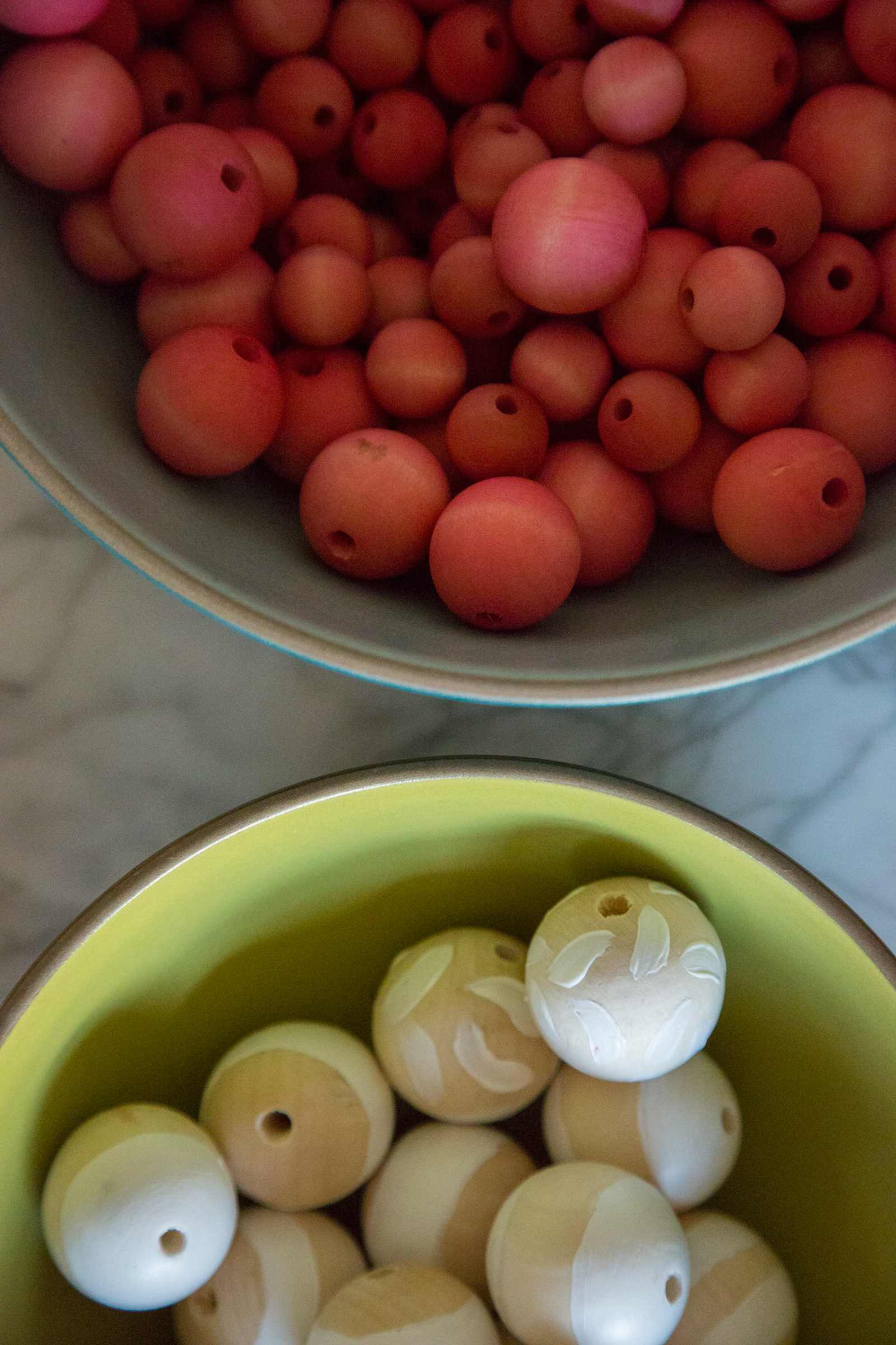 Two bowls of woods beads to make a garland. 