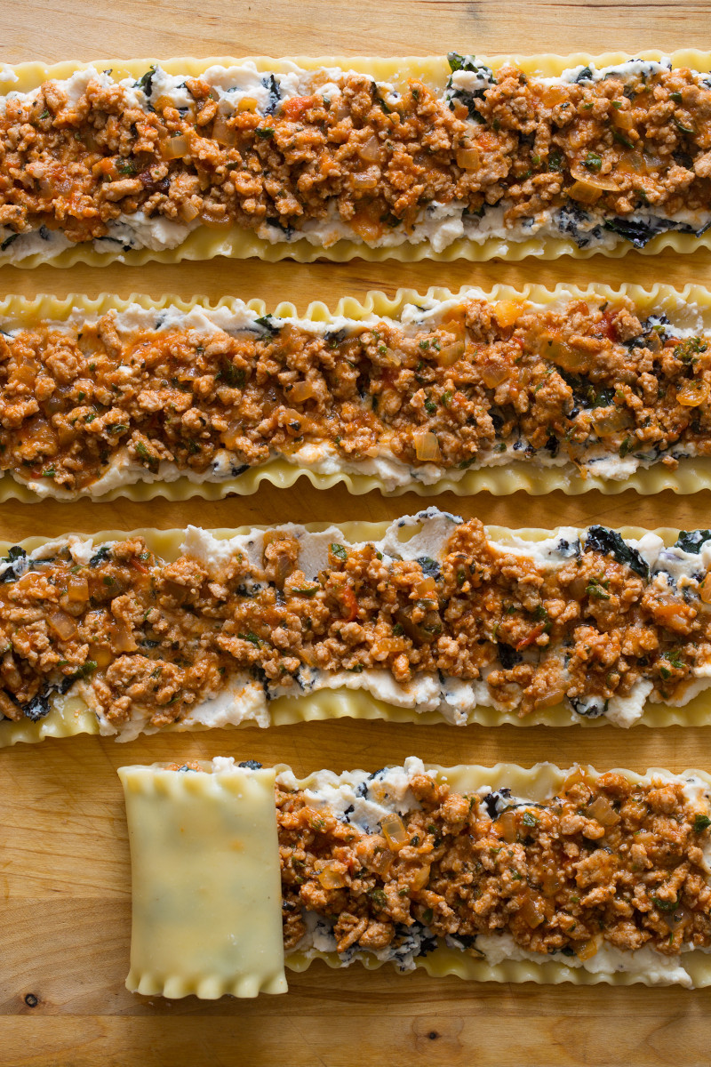 Lasagna noodles laid out with stuffing on top, ready to roll up.