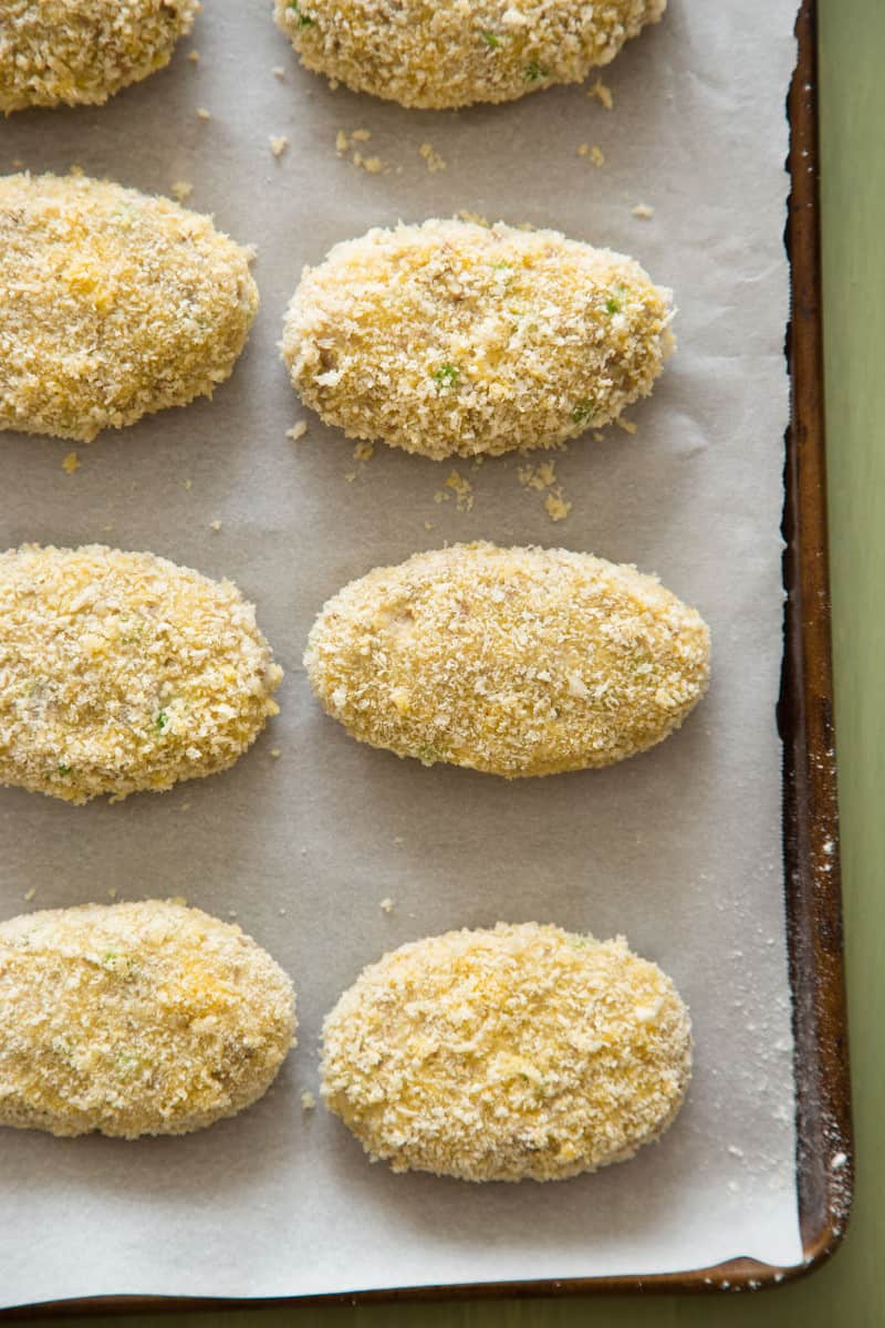 A close up of uncooked korokke on a lined sheet pan.