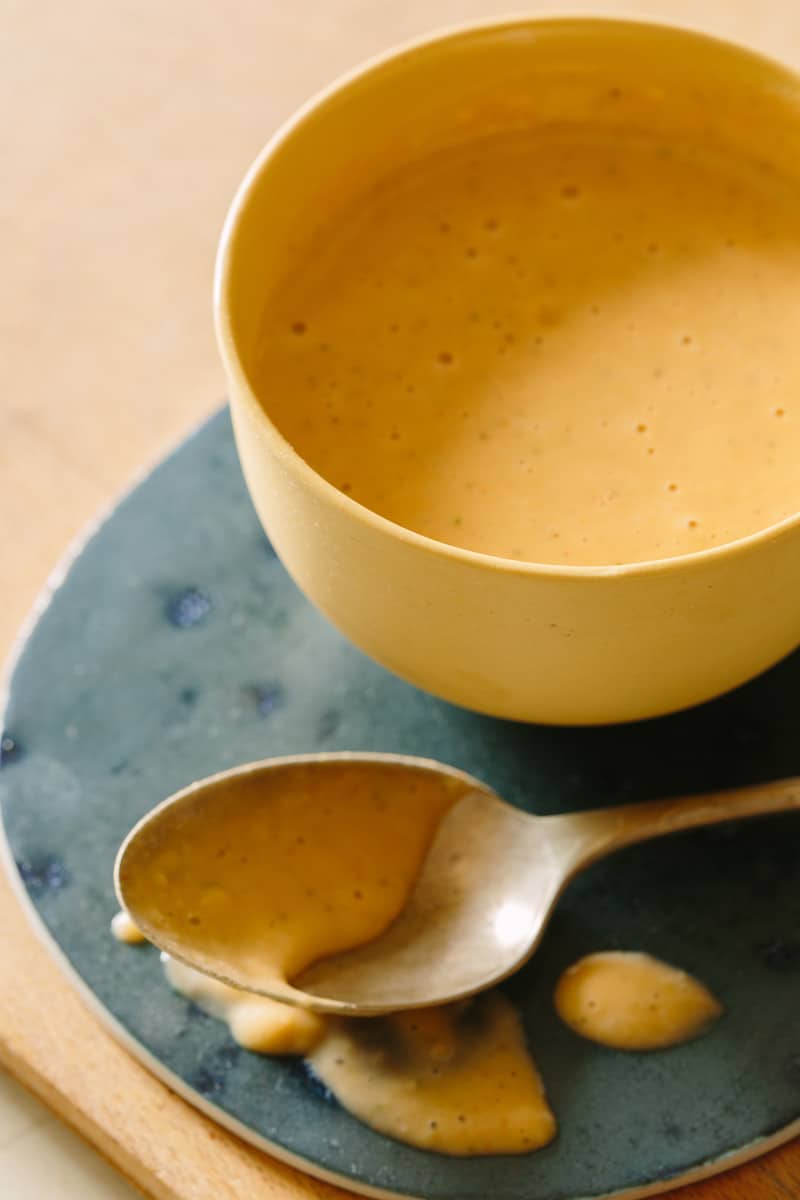 A close up of a bowl of creamy white bean and roasted garlic sauce with a spoon.