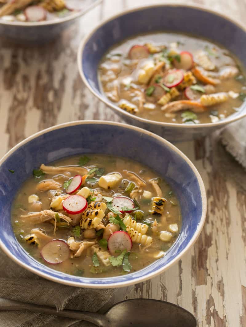 Spicy white bean chili with shredded chicken in blue bowls on a wooden table top.